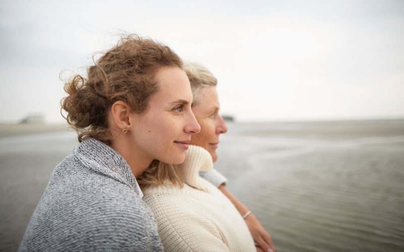 Adult daughter hugging mother on the beach. Adult daughter hugging mother on the beach.